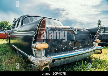 Old abandoned rusty car rusting on green grass. Stock Photo