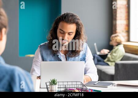 Contemporary mixed-race businessman or office manager sitting in front of laptop Stock Photo