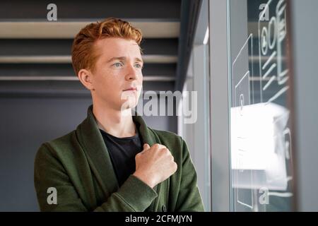 Young serious software developer standing in front of noticeboard with sketches Stock Photo