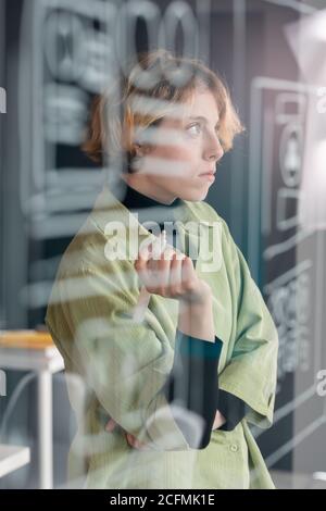 Young pensive female mobile application developer concentrating on work Stock Photo