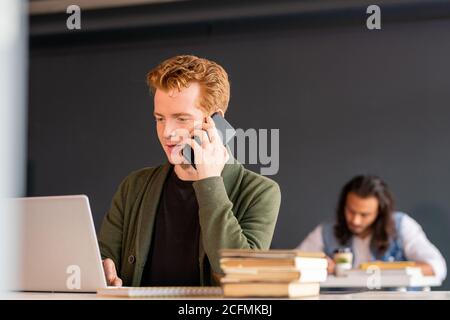 Young agent or office manager with smartphone by ear looking at laptop display Stock Photo