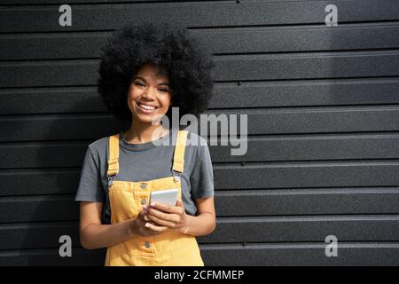 Happy African young hipster woman with Afro hair using smartphone, portrait. Stock Photo