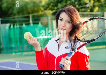 Portrait of a beautiful young female tennis player in sports clothing holding tennis racket on court. Stock Photo