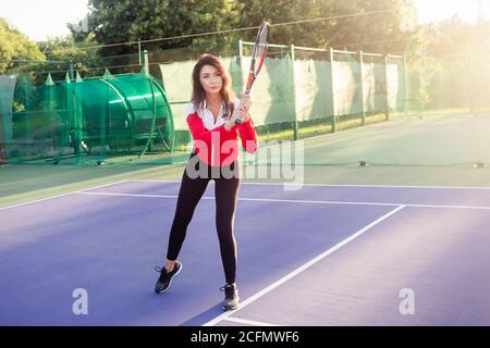 Portrait of a beautiful young female tennis player in sports clothing holding tennis racket on court. Stock Photo