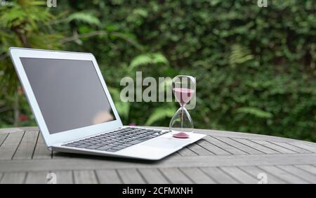 Hourglass on laptop computer. Time management, countdown and deadlines concept. Stock Photo