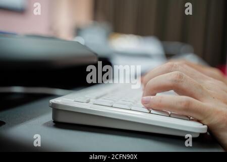 Hand of man typing on pc keyboard over blurred background with copy space Stock Photo