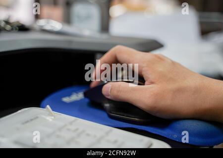 Hand of man using a computer mouse over blurred background with copy space Stock Photo