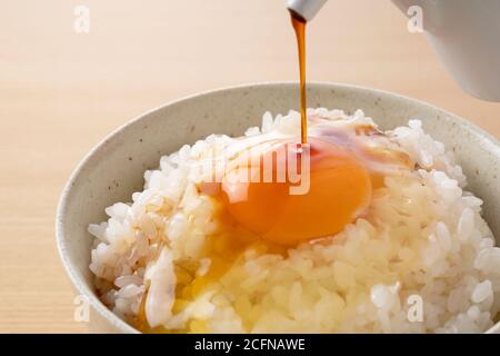 Soy sauce on rice with egg set against a wooden backdrop Stock Photo