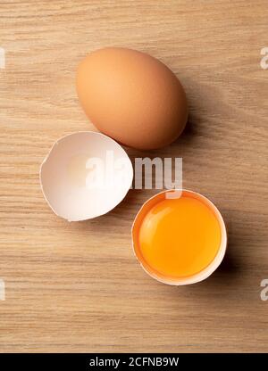 A bird's eye view of the eggs on the wooden table and the broken eggs Stock Photo