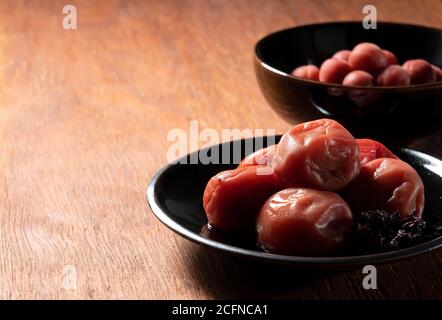 Two types of Japanese pickled plums placed on a wooden background with copy space Stock Photo