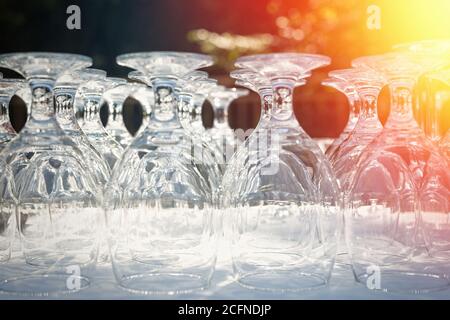 Wine glasses on a table outdoor. Focus blurred foreground, defocused background bokeh, light optical refraction sun flares right corner Stock Photo