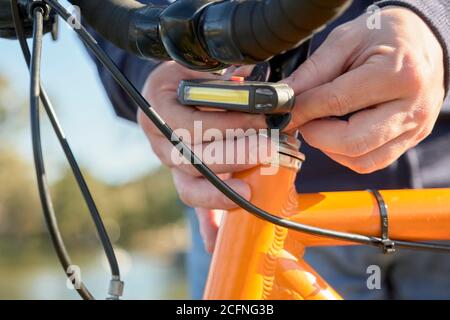 Young man hands putting the headlight on a bike, outdoors Stock Photo