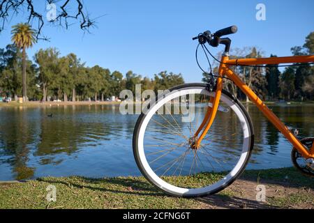 Orange bicycle on the edge of a lake in the large public park known as Bosques de Palermo, in Buenos Aires, Argentina Stock Photo