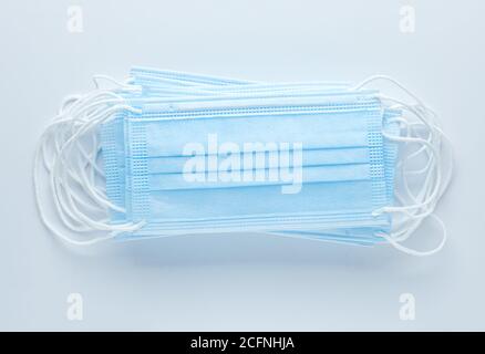 Pile of disposable medical face masks on blue background. Personal protective equipment, PPE. Stock Photo