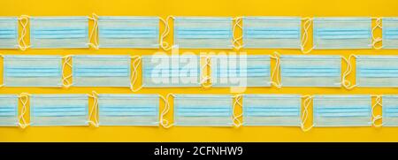 Layout of disposable medical face masks on yellow background. Personal protective equipment, PPE. Stock Photo