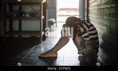 Little child girl sitting near teddy bear with lonely and sadness.Low key style Stock Photo