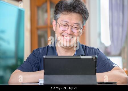 Middle-aged Asian man working at home. Telecommuting concept. Stock Photo