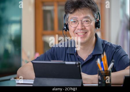 Middle-aged Asian man working at home. Telecommuting concept. Stock Photo