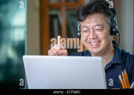 Middle-aged Asian man working at home. Telecommuting concept. Stock Photo