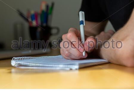 A young man takes notes and calculates while sitting at a desk during a meeting Stock Photo