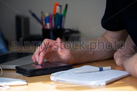 A young man takes notes and calculates while sitting at a desk during a meeting Stock Photo