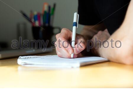 A young man takes notes and calculates while sitting at a desk during a meeting Stock Photo
