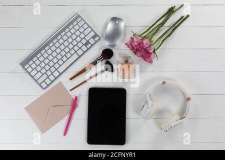 View of a keyword with make up, tablet, flowers and headphones on white wood background Stock Photo