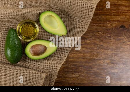 View of two avocados and olive oil bottle on wood table background Stock Photo