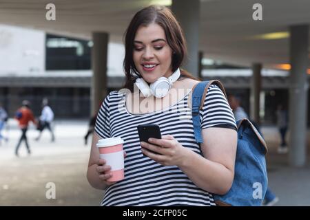 Curvy Caucasian woman using her smartphone in the city streets Stock Photo