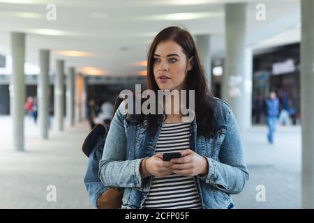 Curvy Caucasian woman using her smartphone in the city streets Stock Photo