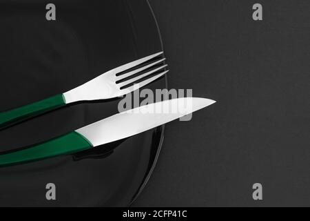 Empty black slate plate, cutlery on dark stone table and napkin. Food background for menu, recipe. Table setting. Flatlay, top view. Mockup for restau Stock Photo