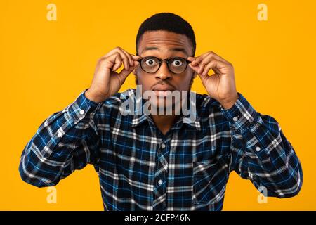 Amazed African American Looking At Camera Through Eyeglasses, Yellow Background Stock Photo