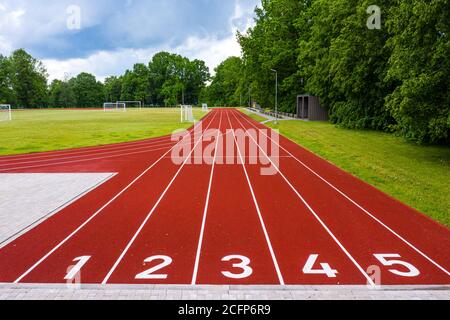 perspective view of an open - air stadium with red numbered running tracks, infrastructure for sports activities Stock Photo