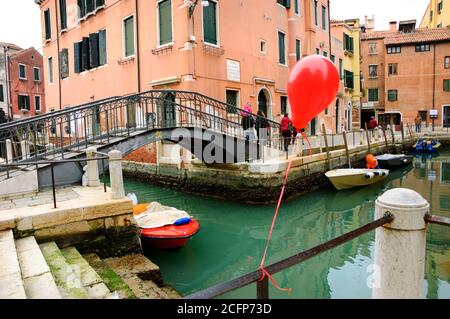 VENICE, ITALY - FEBRUARY 14, 2015: Balloon lost at the Carnival party attached to the canal railing. The Carnival in Venice is annual event. Stock Photo