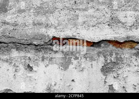 cracked concrete wall with a large crack and red bricks underneath. Destruction and ruin concept Stock Photo
