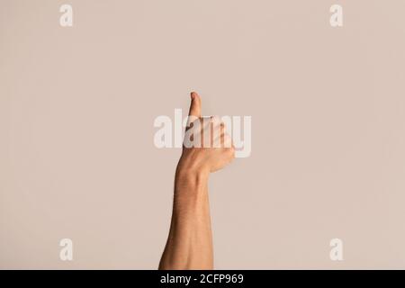 Cropped view of young guy showing thumb up gesture, expressing approval on light background Stock Photo