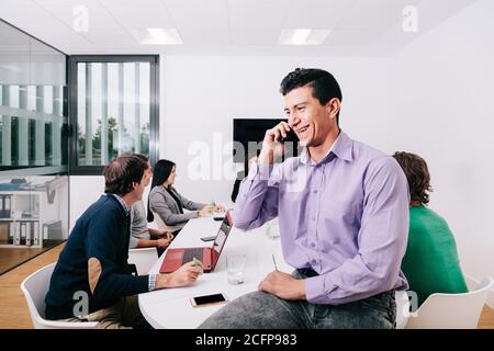 A businessman talking on cell phone sitting at the office table Stock Photo