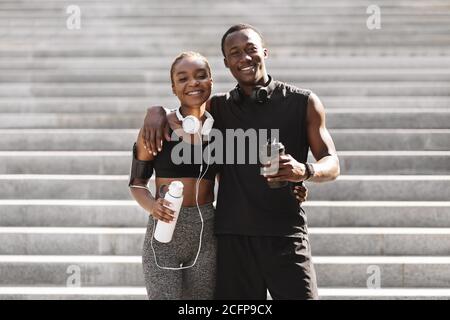 Happy black couple posing outdoors after exercising in park, looking at camera