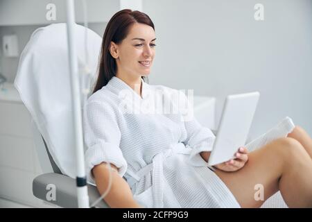 Smiling spa client using a gadget during a medical procedure Stock Photo