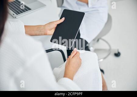 Woman with a gadget having a consultation with a cosmetician Stock Photo