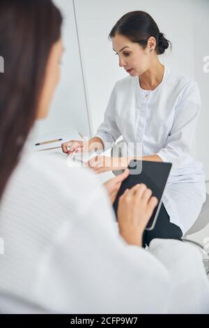 Dermatologist using her gadget during the consultation Stock Photo