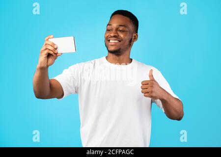 African American Man Making Selfie Gesturing Thumbs-Up Over Blue Background Stock Photo