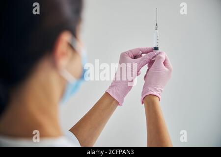 Dermatologist in a face mask preparing for giving an injection Stock Photo