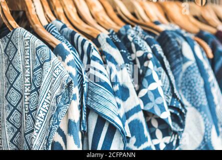 Selective focus tie dye shirts in blue white clothing hanging on rack. Stock Photo