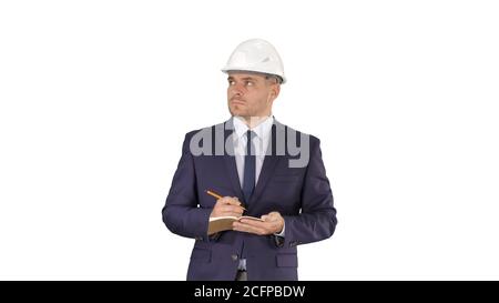 Engineer in suit and helmet walking and writing notes in notepad on white background. Stock Photo