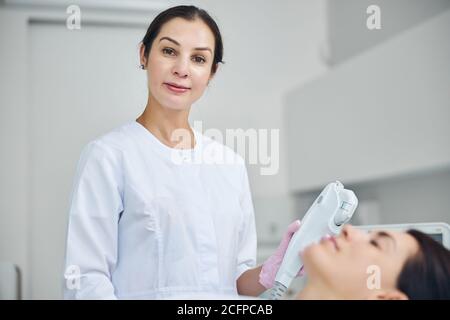 Doctor with an ultrasonic facial device posing for the camera Stock Photo