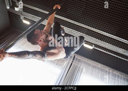 Handsome man performing pole dance moving on pole Stock Photo
