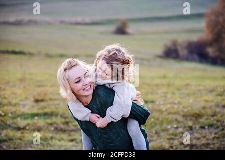 Small girl with mother on a walk in autumn nature, having fun. Stock Photo