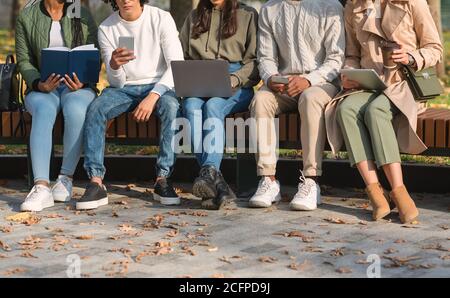 Friends spending time in park, studying, using cellphones Stock Photo