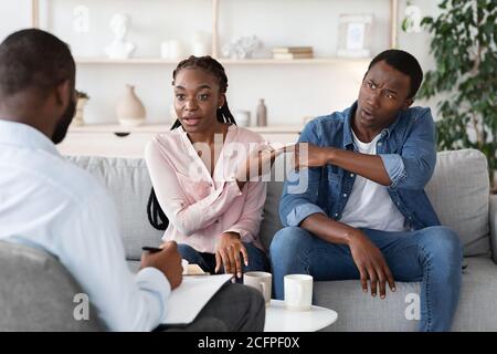 Young Black Couple Blaming Each Other In Relationship Problems At Counselor's Office Stock Photo